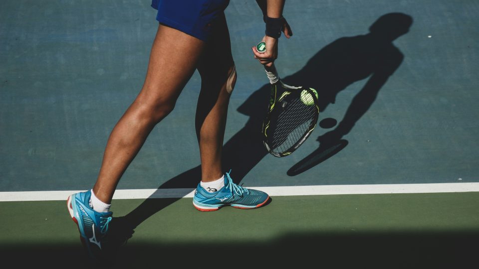 woman holding tennis ball and racket