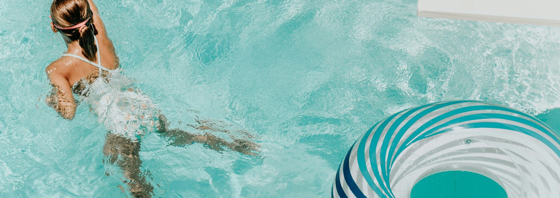 girl wearing swimsuit and swims in swimming pool